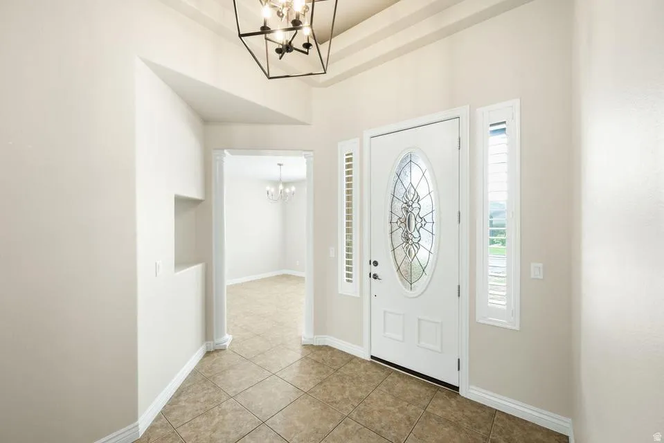 Foyer with suspended lighting and light tile patterned flooring