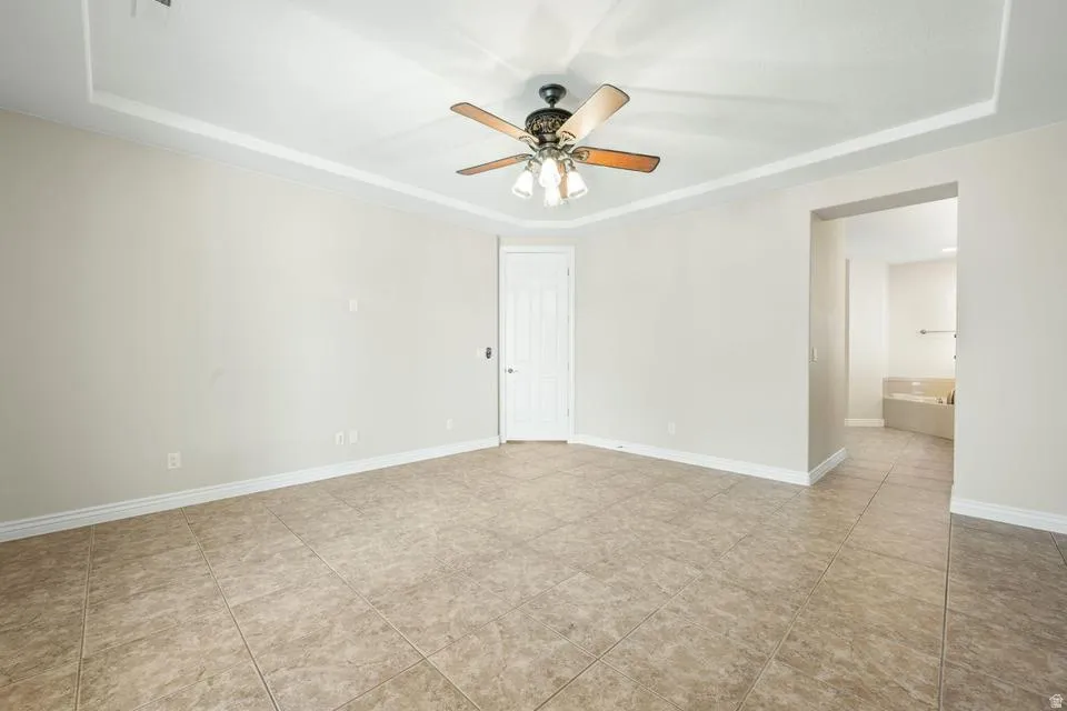 Unfurnished room featuring a tray ceiling and ceiling fan