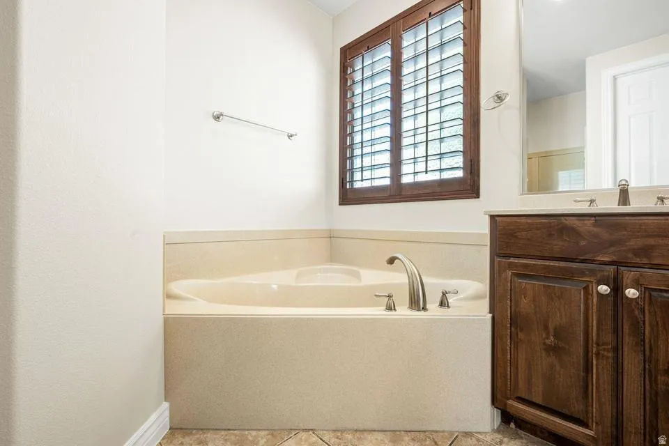 Full bathroom with a garden tub, vanity, and light tile patterned flooring