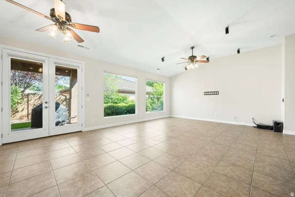 Spare room with a ceiling fan, vaulted ceiling, french doors, and light tile patterned flooring