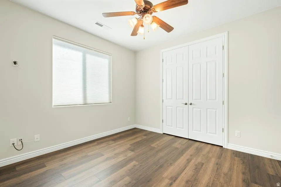 Unfurnished bedroom featuring dark wood-type flooring, a ceiling fan, and a closet