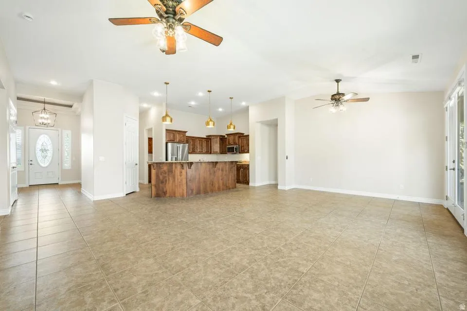 Unfurnished living room with ceiling fan, healthy amount of natural light, and hanging lights