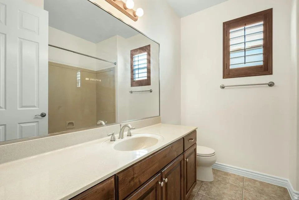 Full bath featuring vanity, light tile patterned flooring, and a shower
