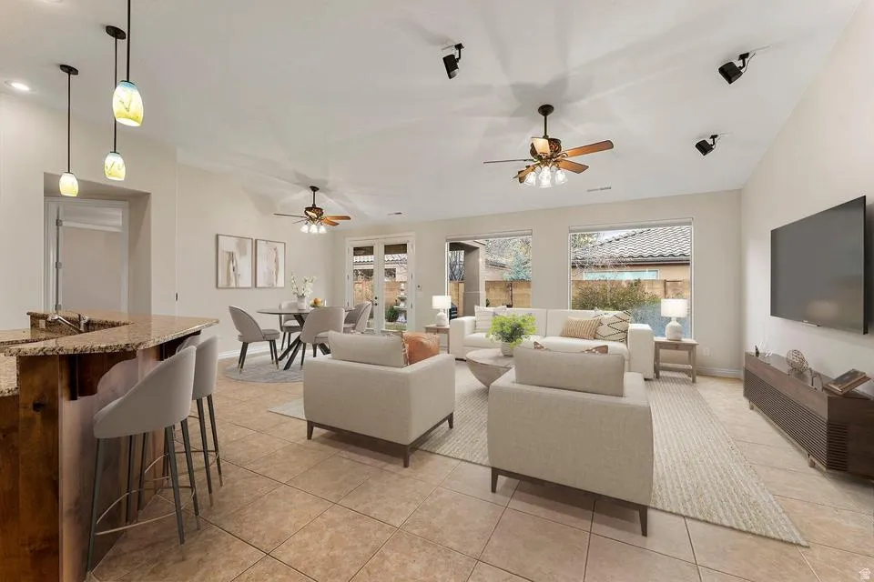 Living room featuring light tile patterned floors, ceiling fan, and vaulted ceiling