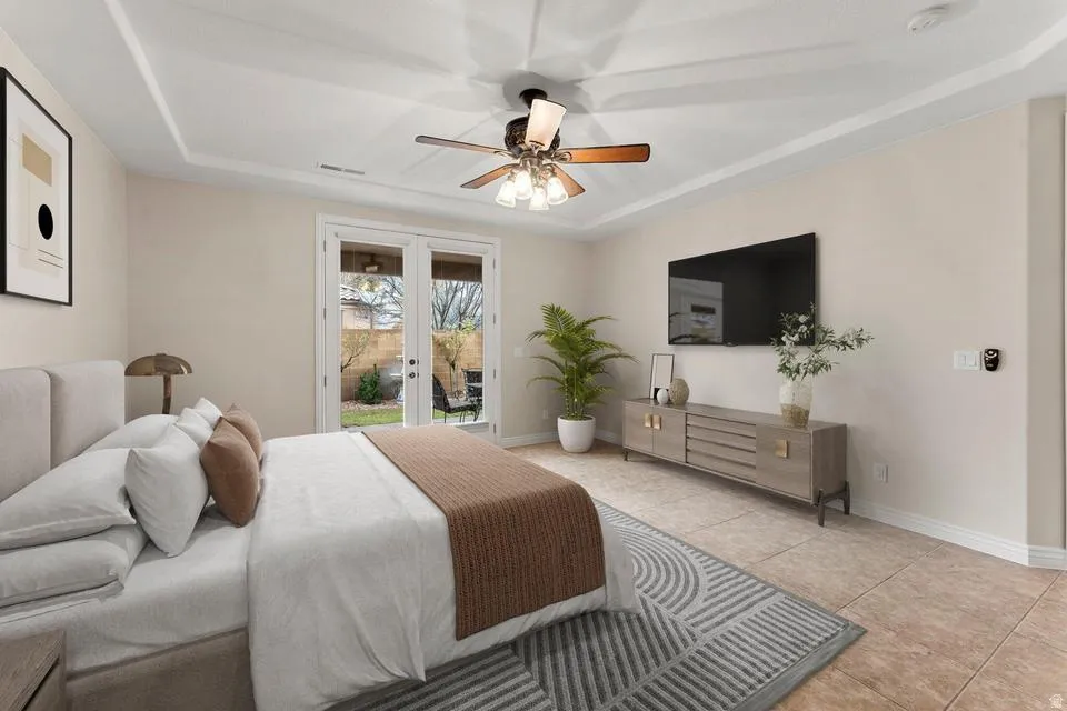 Bedroom with french doors, access to outside, a tray ceiling, ceiling fan, and light tile patterned floors