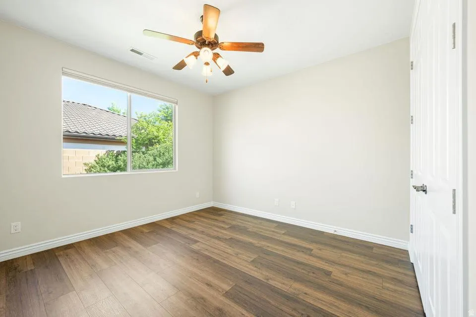 Spare room featuring dark wood-style floors and a ceiling fan