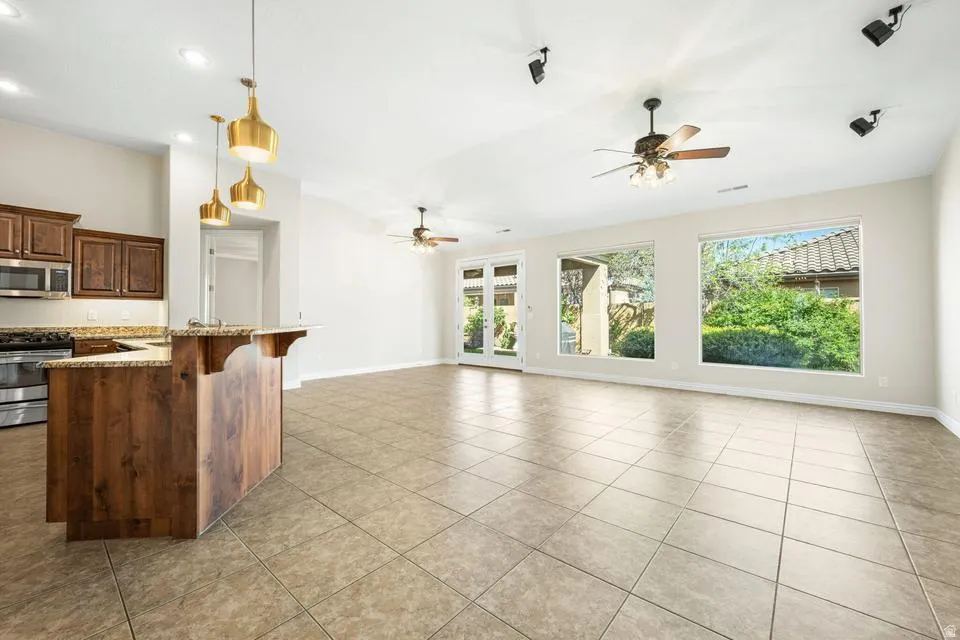 Kitchen with stainless steel appliances, light stone countertops, open floor plan, a ceiling fan, and a kitchen breakfast bar