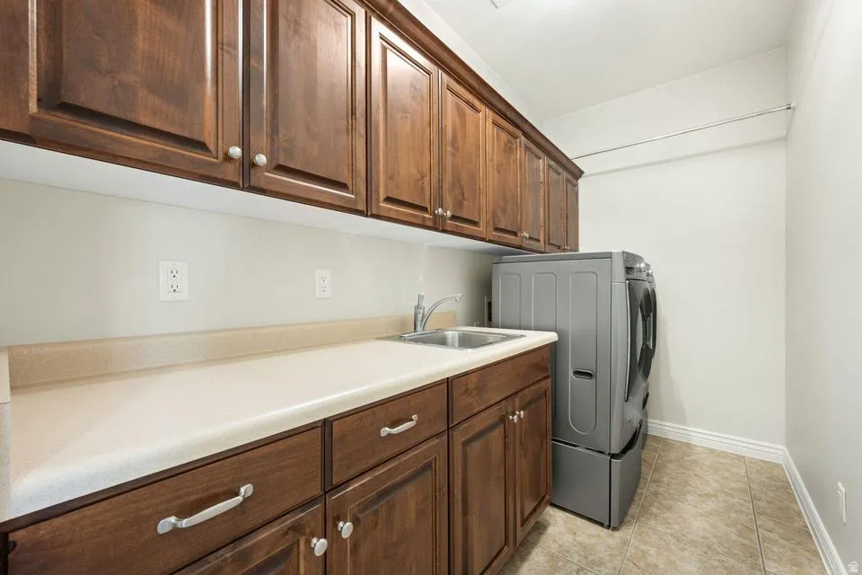 Laundry room with cabinet space, washer / clothes dryer, and light tile patterned floors