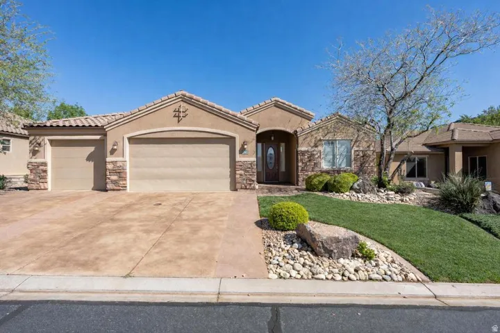Mediterranean / spanish-style home with stone siding, a garage, stucco siding, driveway, and a tiled roof