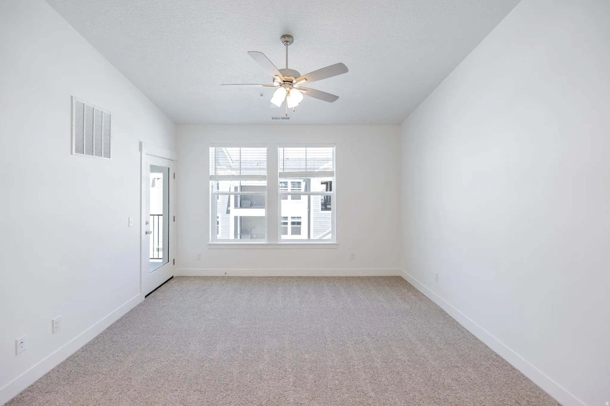 Recessed lighting, ceiling fan with integrated lighting, dual windows with blinds, glass-paneled door, and neutral-toned carpeting
