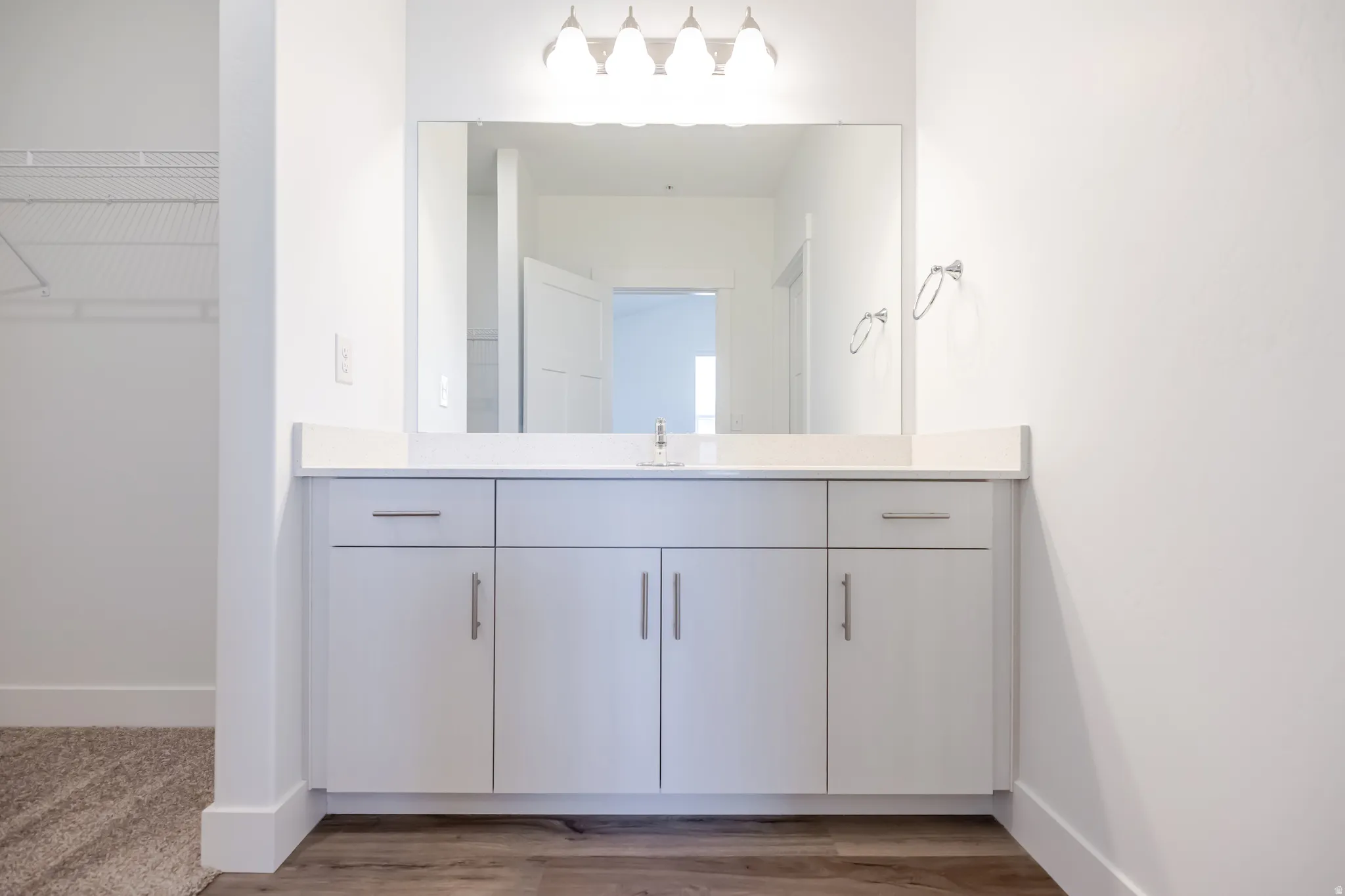 Vanity with integrated sink, white cabinetry, and a large wall-mounted mirror