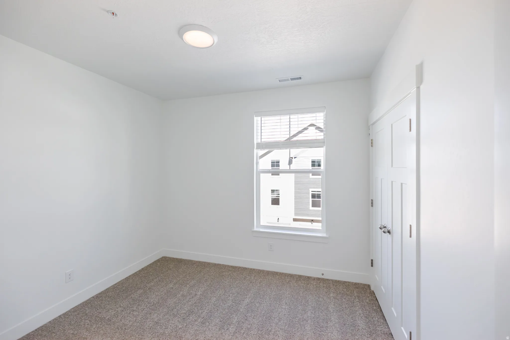 Recessed ceiling light, neutral carpet, white walls, double-door closet, and white window blinds