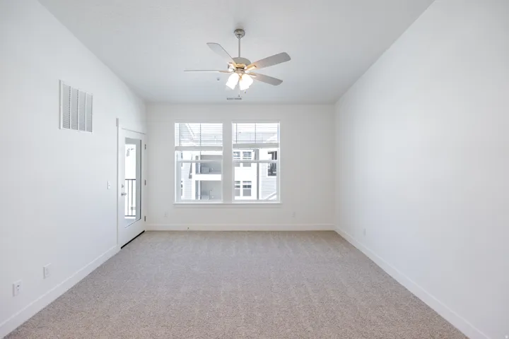 Recessed lighting, ceiling fan with integrated lighting, dual windows with blinds, glass-paneled door, and neutral-toned carpeting