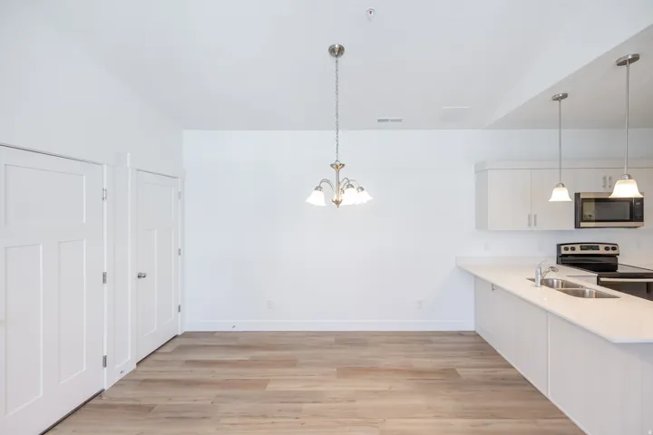 Open-concept dining area with wood-finish flooring, a multi-light chandelier, and white paneled doors