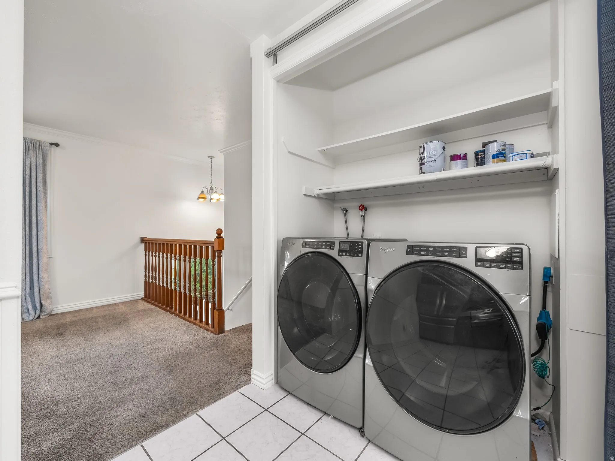 Laundry area featuring light colored carpet, washer and dryer, and light tile patterned floors