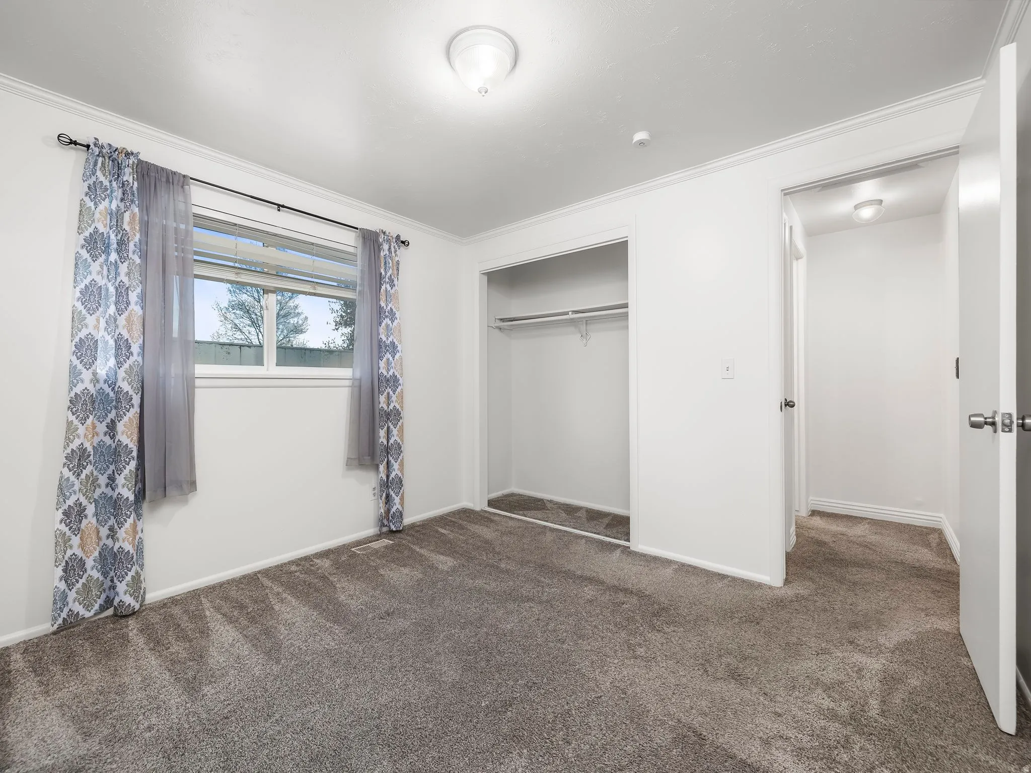 Unfurnished bedroom with dark carpet, a closet, and crown molding
