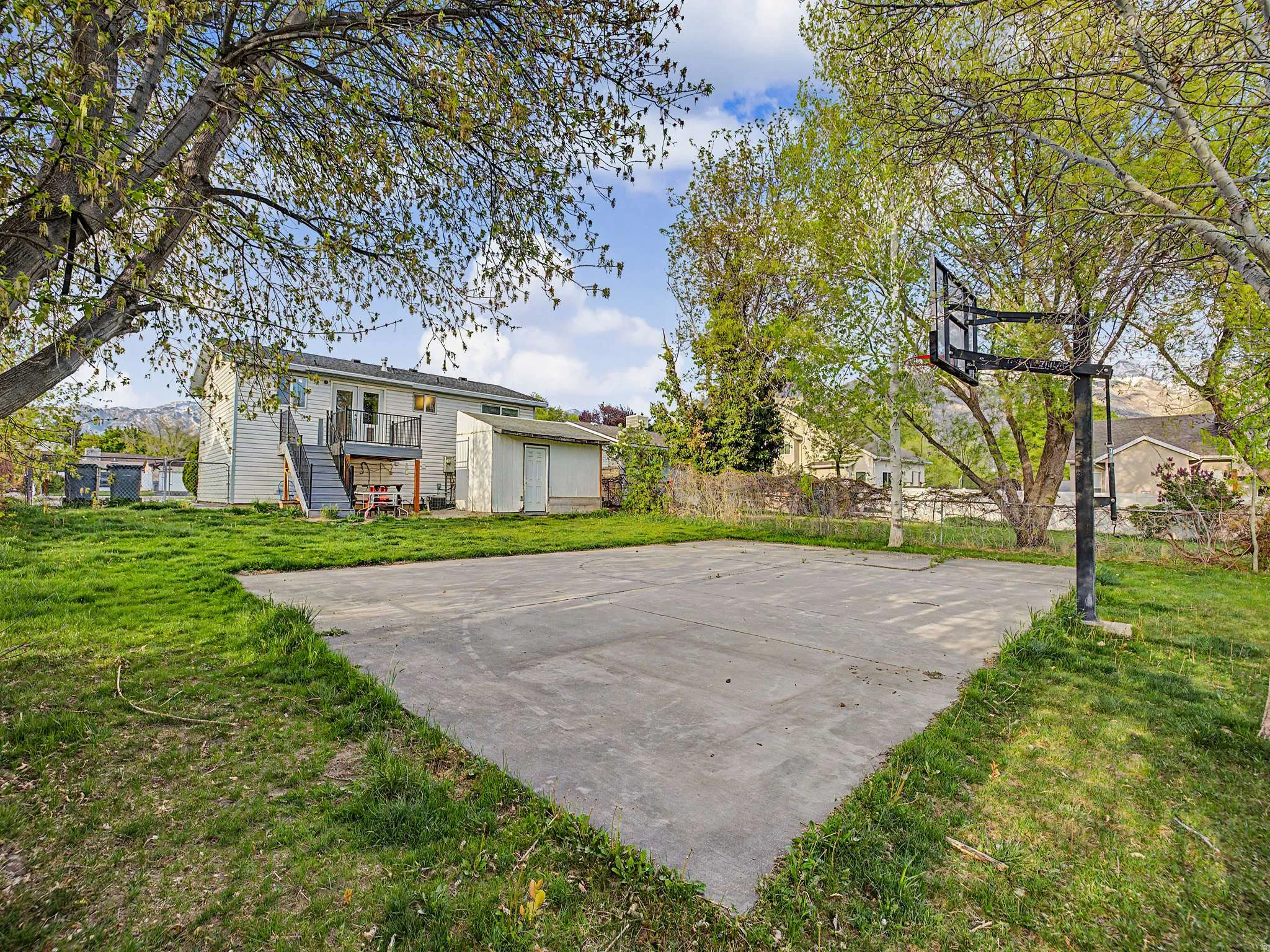 View of basketball court featuring basketball hoop and a shed
