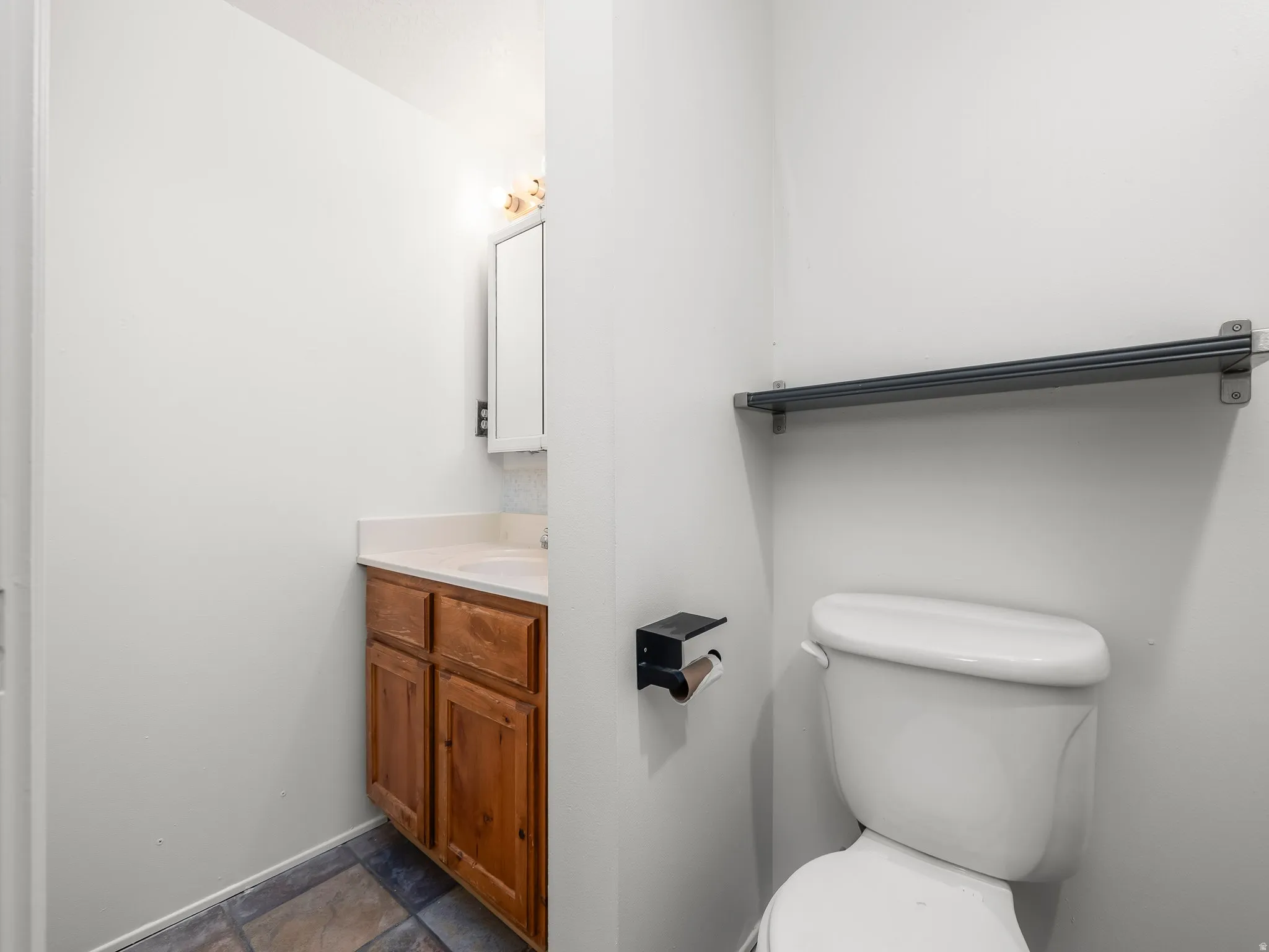Half bath featuring vanity and dark stone finish floors