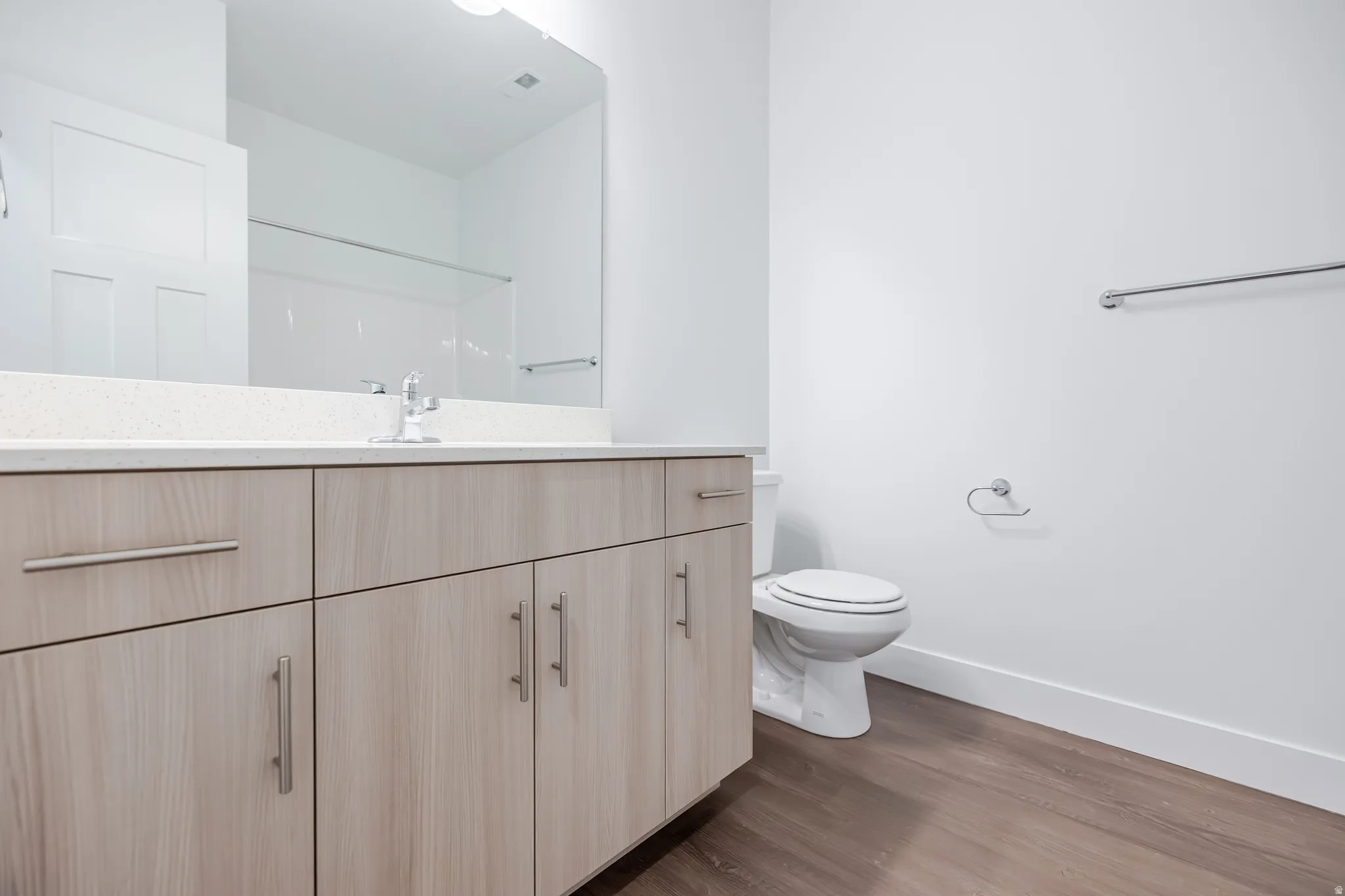 Spacious vanity with light wood-finish cabinetry, a large integrated mirror, and a white countertop
