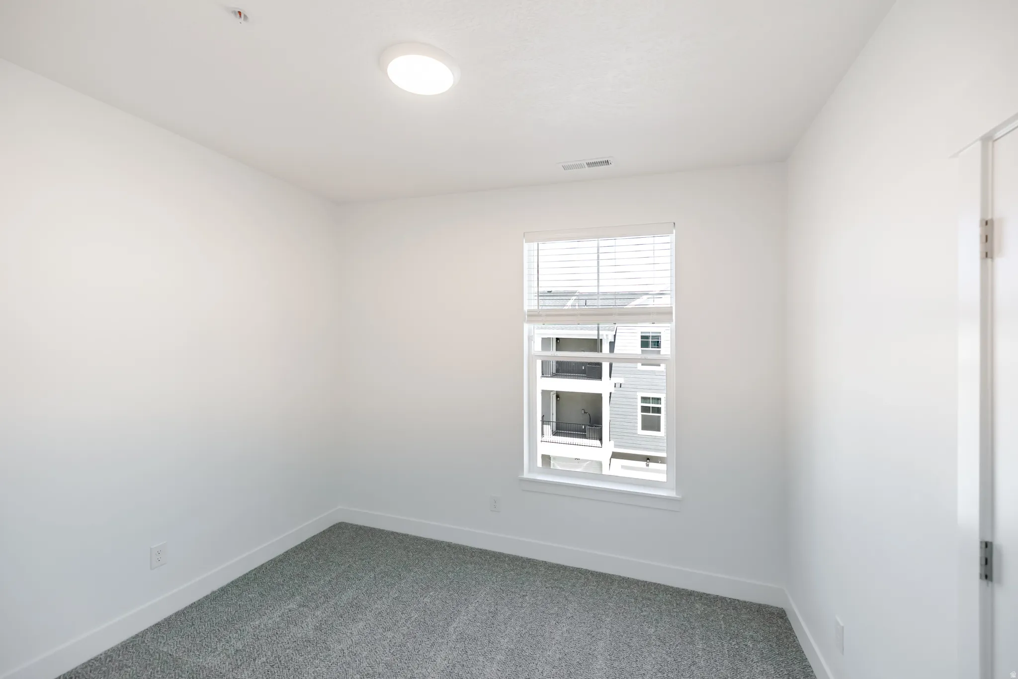 Neutral wall paint, recessed ceiling lighting, window with blinds, and gray carpeting
