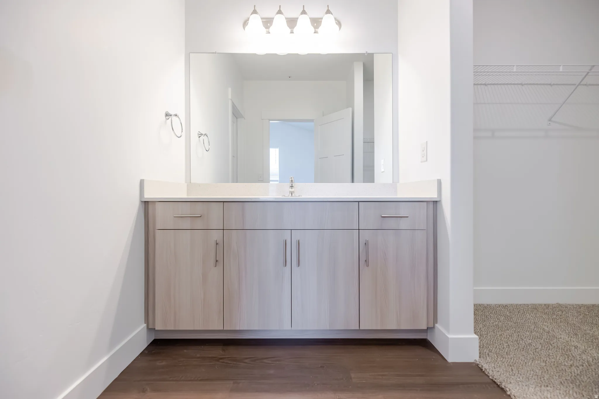 Light wood-finish vanity with a light-toned countertop, undermount sink, and a framed mirror
