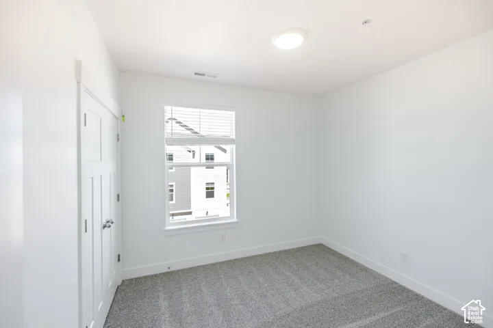 Plush carpet flooring, white interior walls, a window with blinds, and a flush-mount ceiling light fixture