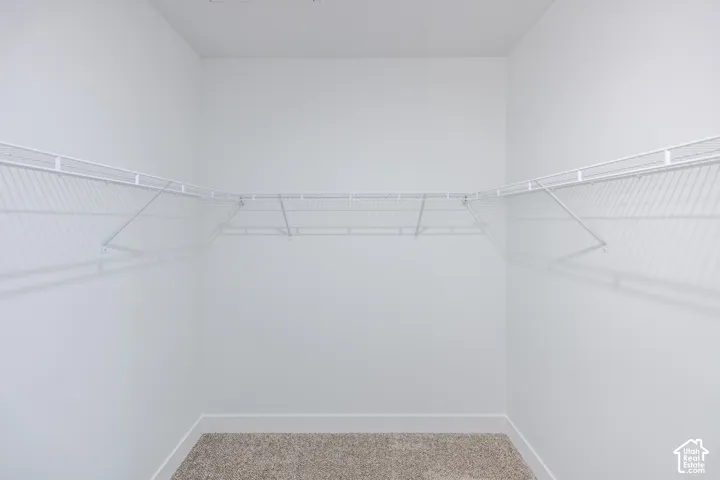 Built-in wire shelving with corner wrap-around configuration, neutral carpet flooring, and white wall finishes