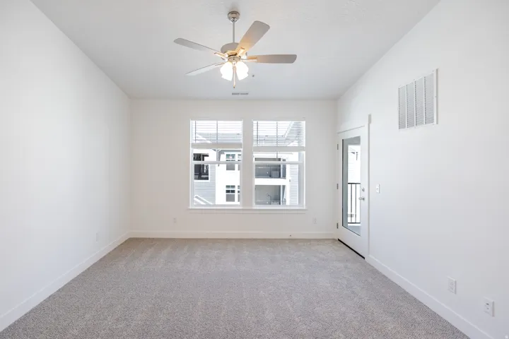 Recessed ceiling fan with integrated lighting, two large windows with blinds, a glass-paneled exterior door, and light gray carpeting