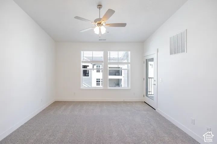 Recessed ceiling fan with integrated lighting, two large windows with blinds, a glass-paneled exterior door, and light gray carpeting
