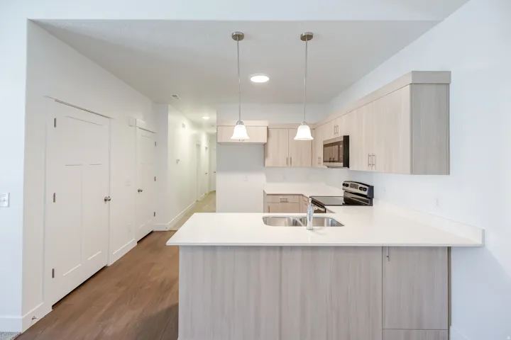 Kitchen featuring light wood-finish cabinetry, white countertops, stainless steel sink with chrome faucet, and recessed lighting