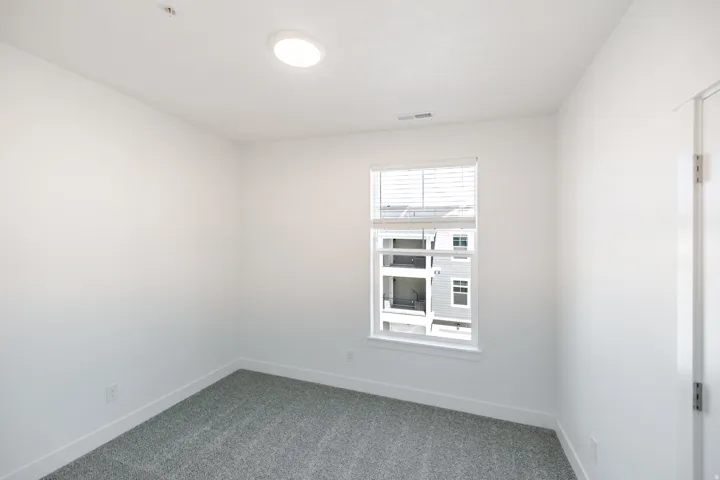 Neutral wall paint, recessed ceiling lighting, window with blinds, and gray carpeting