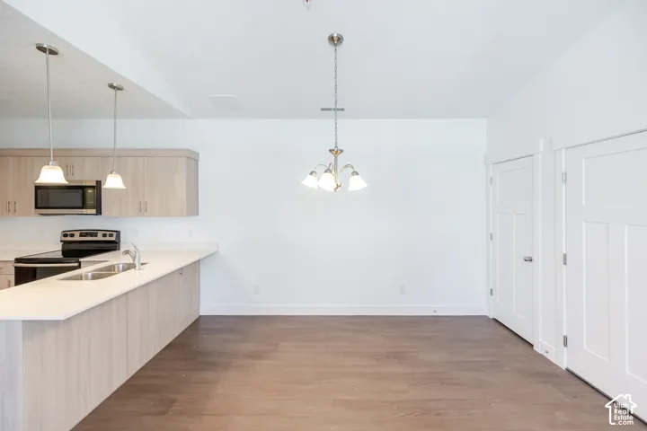 Kitchen featuring light wood-finish cabinetry, stainless steel sink, and light-toned countertops