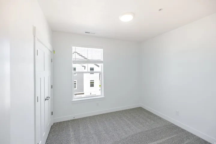 Plush carpet flooring, white interior walls, a window with blinds, and a flush-mount ceiling light fixture