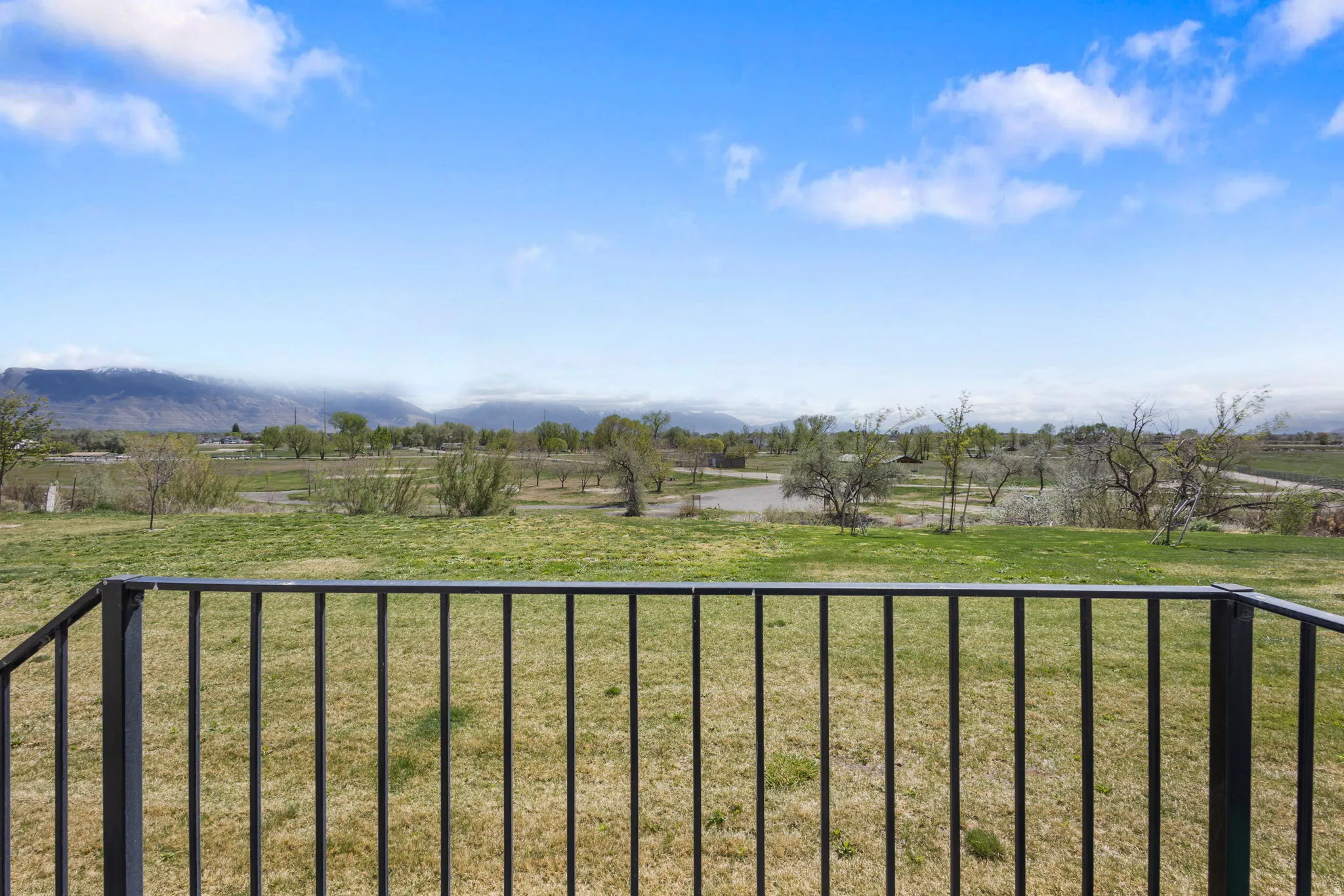 View of green lawn with a rural view and a balcony