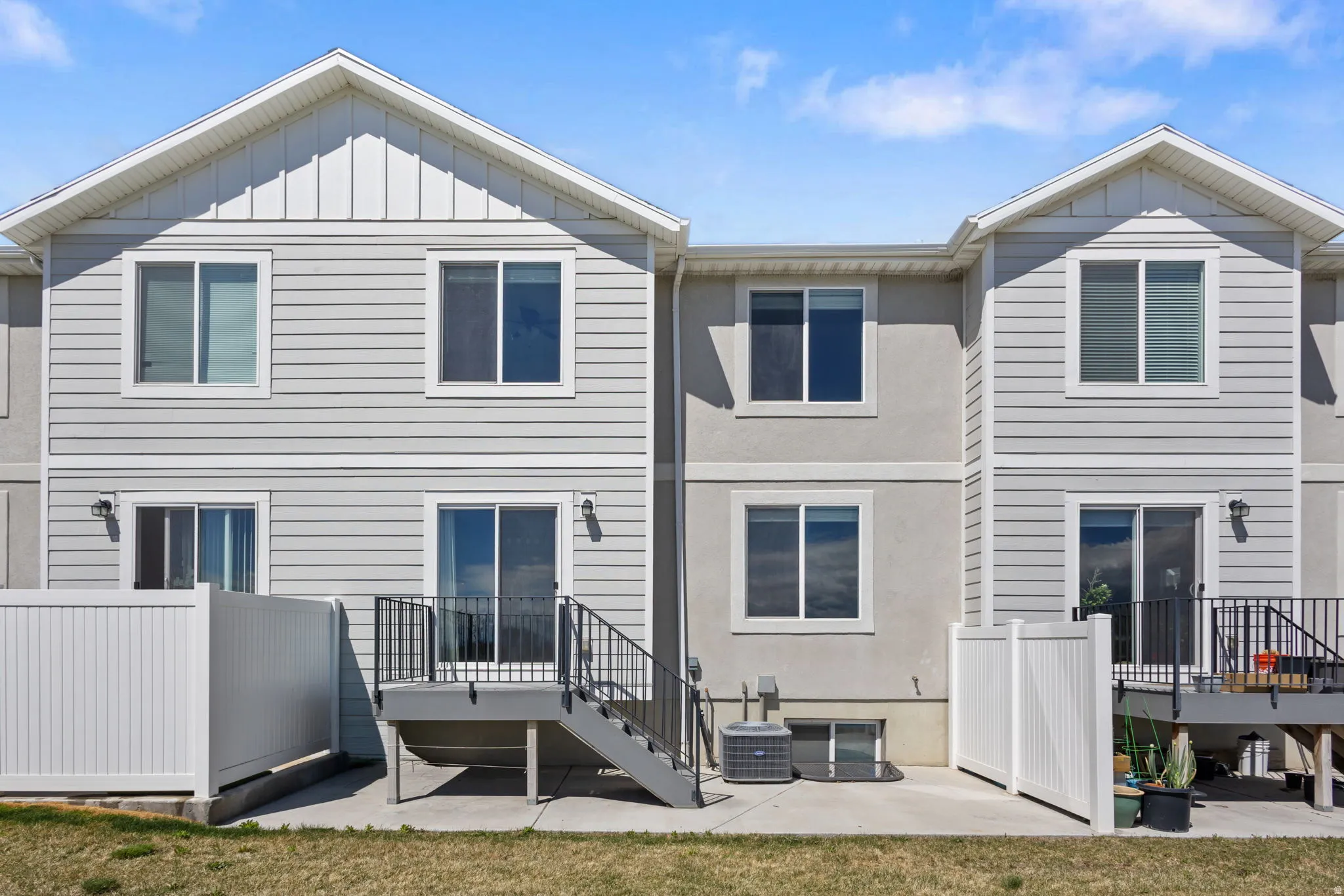 Rear view of house featuring a patio, board and batten siding, a wooden deck, and a yard