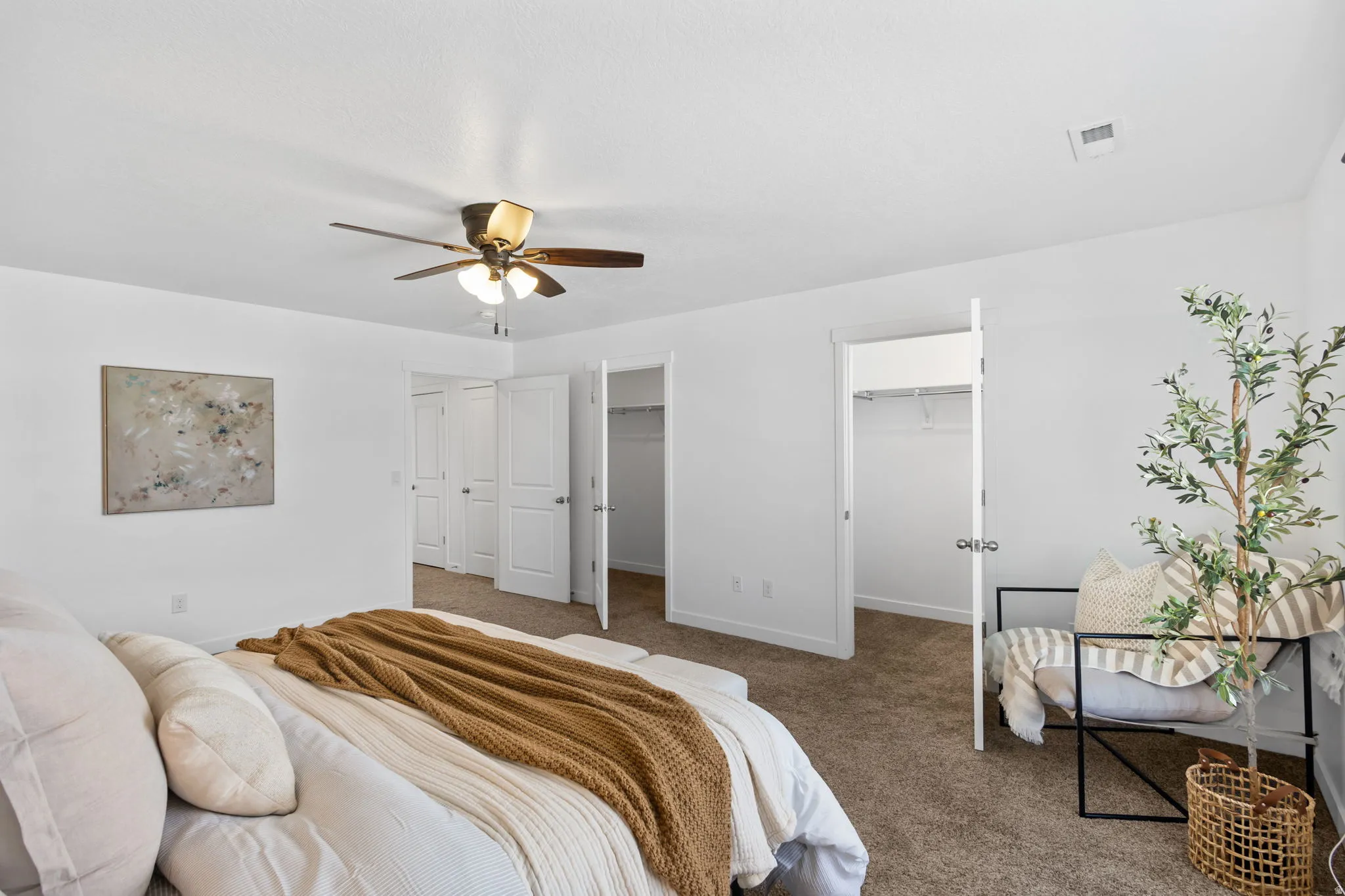 Carpeted bedroom featuring two closets, ceiling fan, and a walk in closet