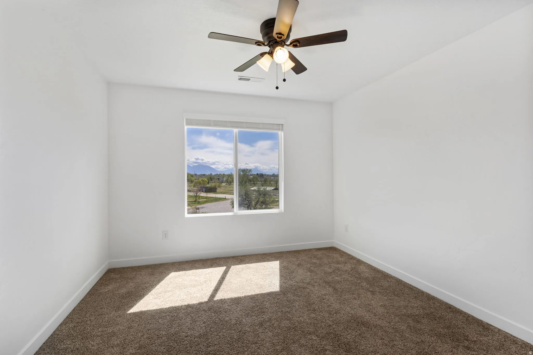 Carpeted spare room featuring a mountain view and ceiling fan