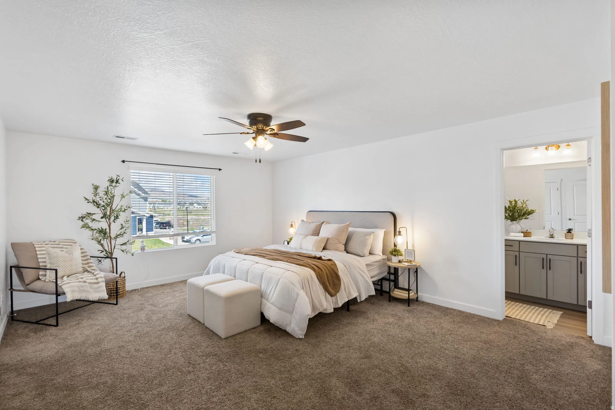 Carpeted bedroom featuring a ceiling fan, ensuite bathroom, and a textured ceiling