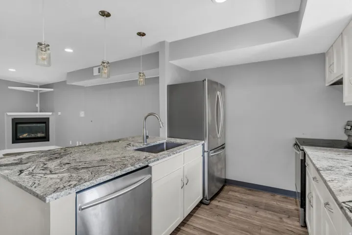 Kitchen with stainless steel appliances, white cabinets, a peninsula, and light wood-style floors