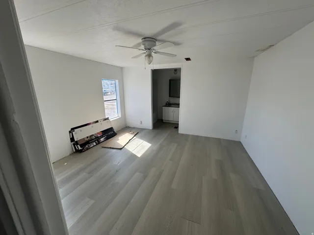 Unfurnished bedroom featuring a ceiling fan, light wood-type flooring, and ensuite bathroom