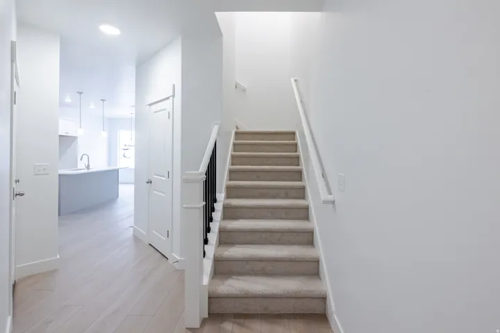 Modern staircase with carpeted treads and a black wrought iron baluster