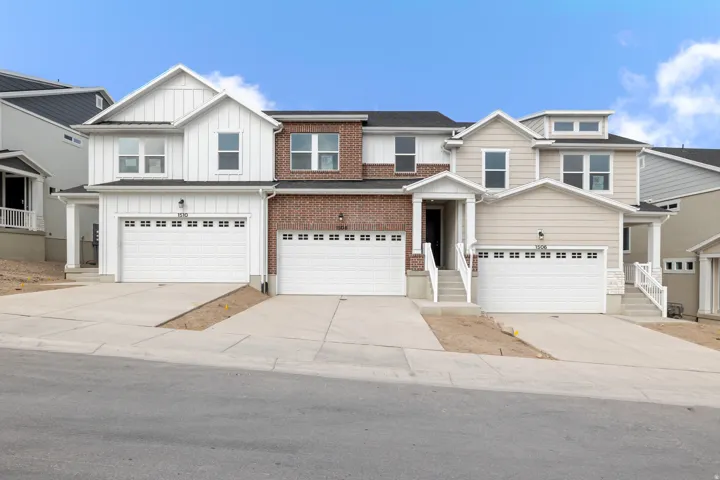 White board-and-batten siding with brick accents and attached two-car garage