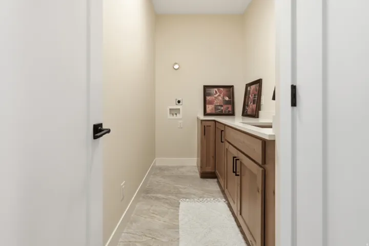 Dedicated utility room featuring wood-finish cabinetry, light-toned countertops, and tile flooring