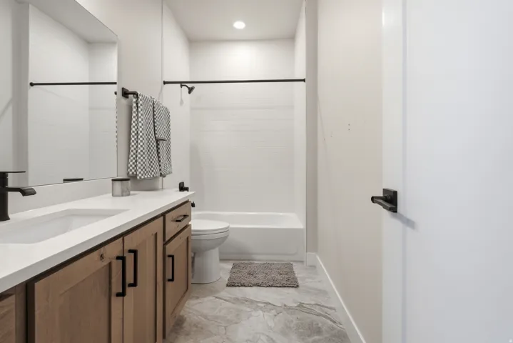 Bathroom featuring a wood-finish vanity with a light-colored countertop, integrated sink, and matte black fixtures