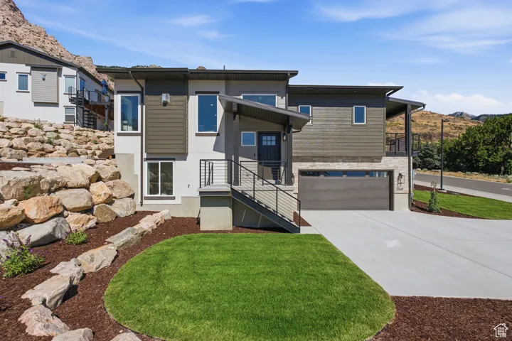 Contemporary multi-level residence featuring a gray exterior, stone accents, and dark wood-finish siding