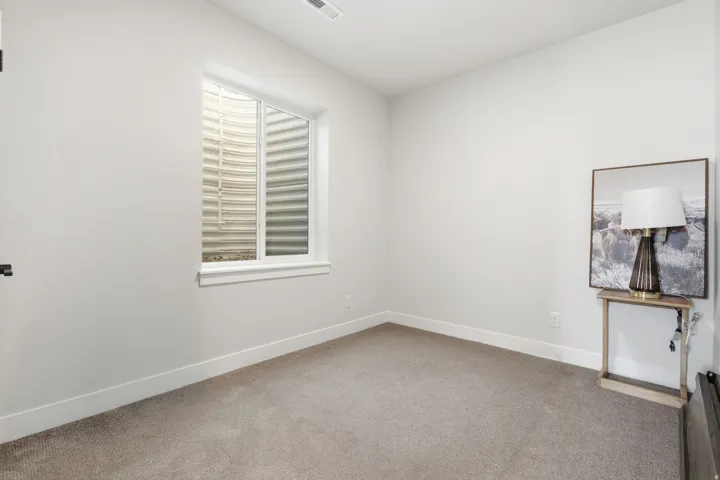 Room featuring a window with a window well, light-colored walls, and neutral carpet flooring