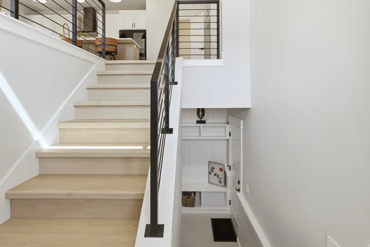 Staircase featuring wood-finish treads and risers with a contemporary black metal railing