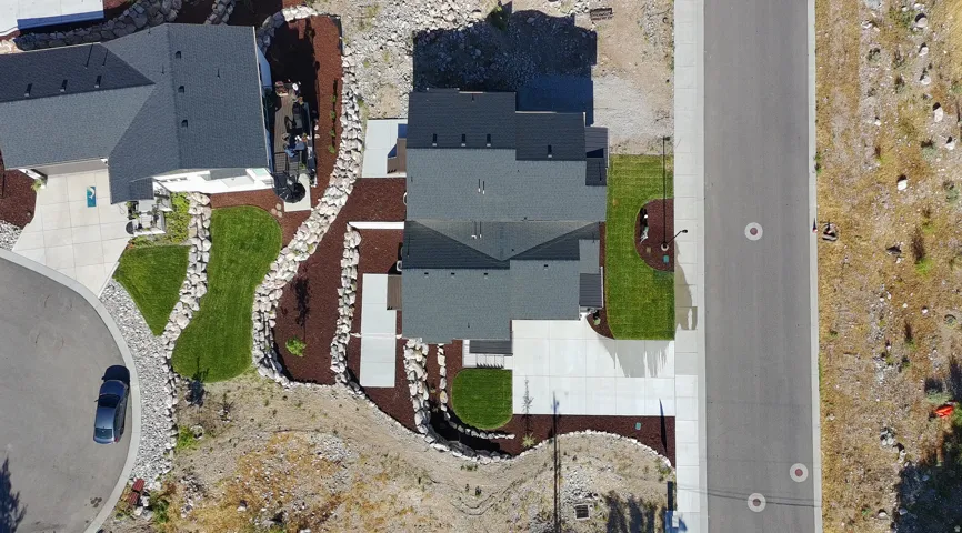 Aerial view of a contemporary property featuring a dark shingle roof and concrete driveway