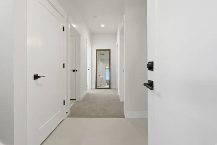 Bright hallway featuring light tile flooring and plush carpeting