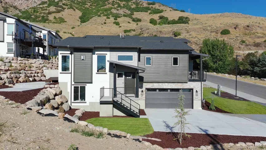 Contemporary exterior with mixed material facade, featuring a two-car garage, concrete driveway, and an elevated front entry with modern railings